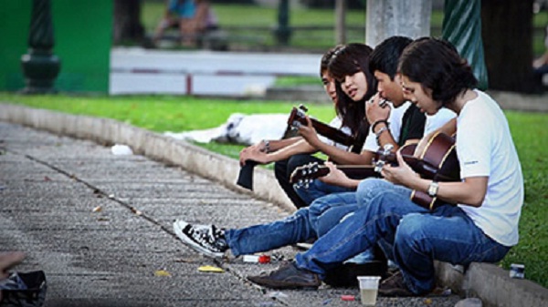 The students playing acoustic guitars in the park