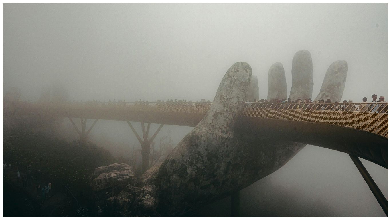 A mysterious view of the Golden Bridge Vietnam shrouded in heavy morning fog, with the iconic giant stone hands emerging from the mist