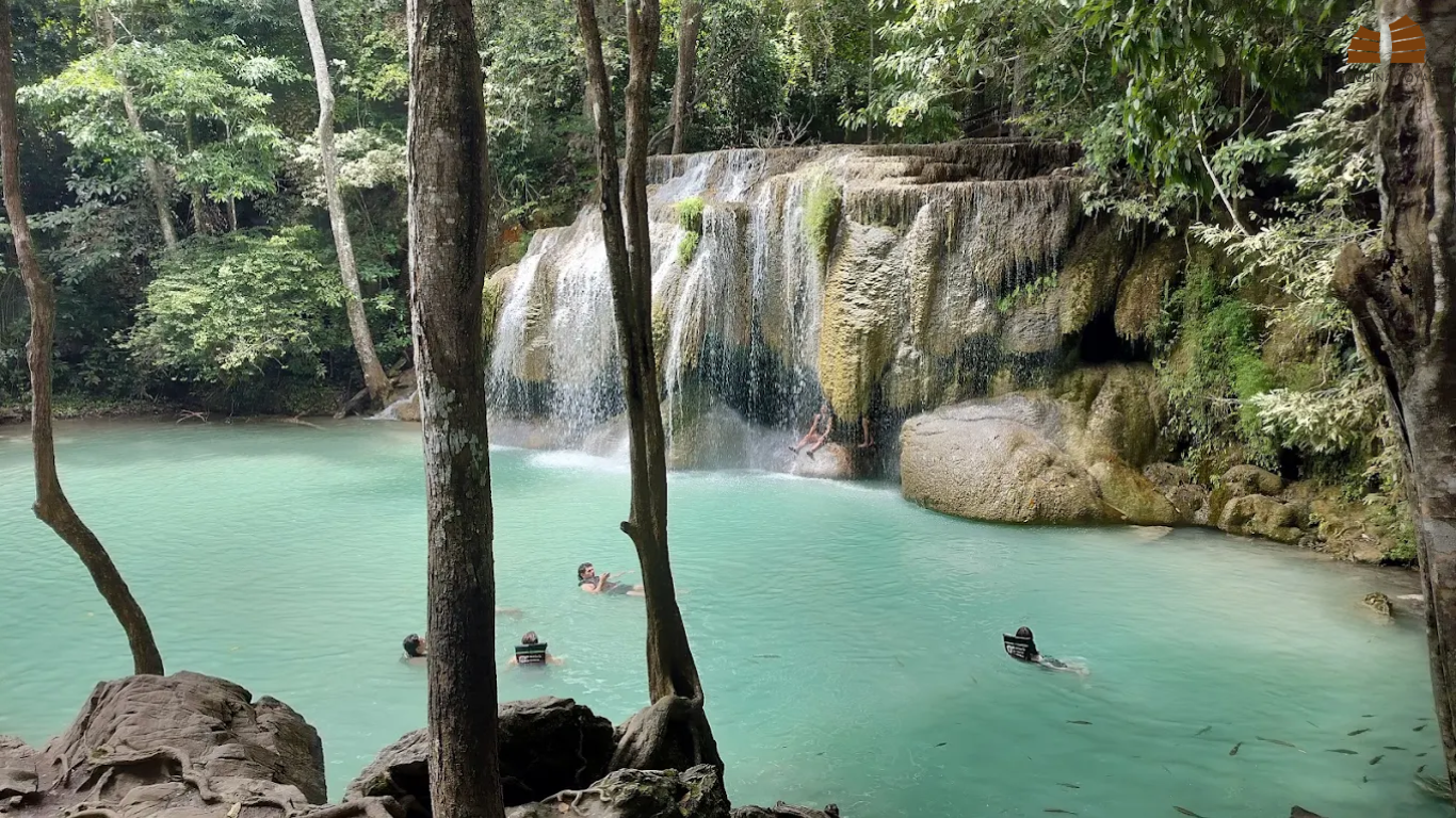 Travelers swimming in the turquoise pools of Erawan Waterfalls
