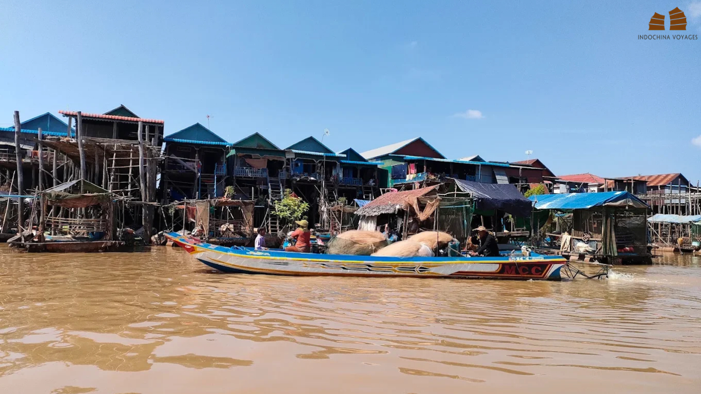 Boat passing tall stilt houses on the water at Kampong Phluk