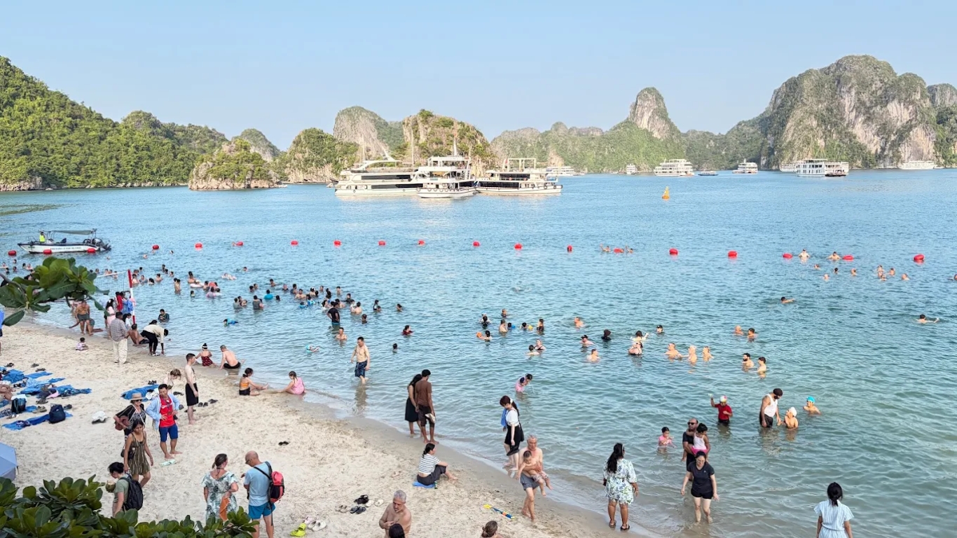 Ti Top Island beach with swimmers and Halong Bay cruise boats