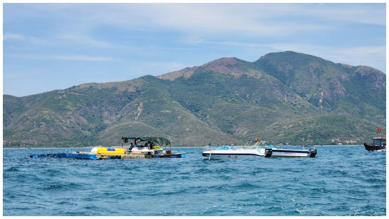Scenic view of Nha Trang bay with speedboats and lush green mountains under a blue sky
