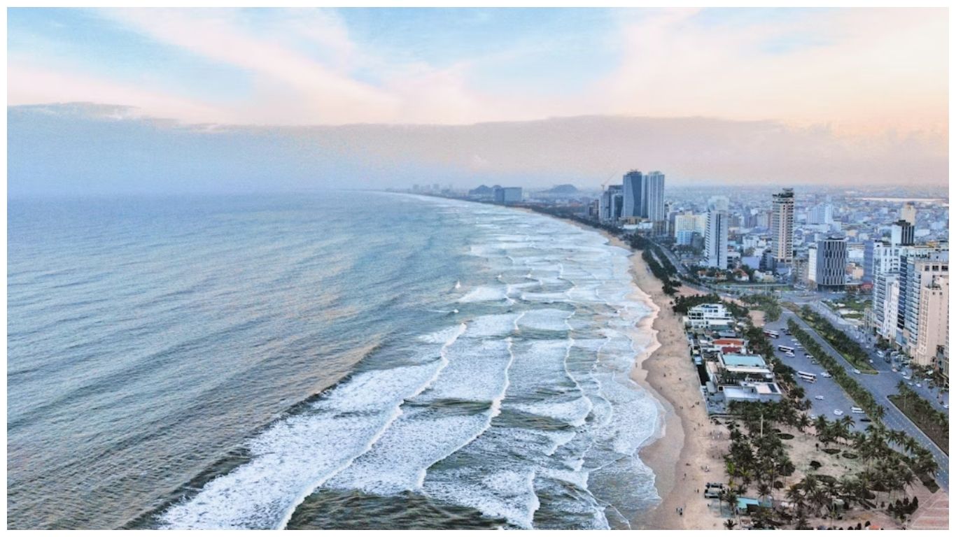 An aerial panoramic view of My Khe Beach in Da Nang, Vietnam, showing the long coastline, white waves, and city skyline to help travelers decide how many days in Da Nang to visit