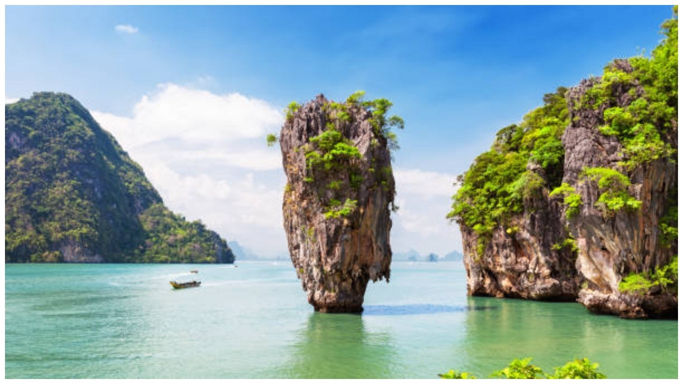 The iconic James Bond Island in Phang Nga Bay near Phuket, showcasing a boat tour experience in Thailand in July with clear skies and emerald waters