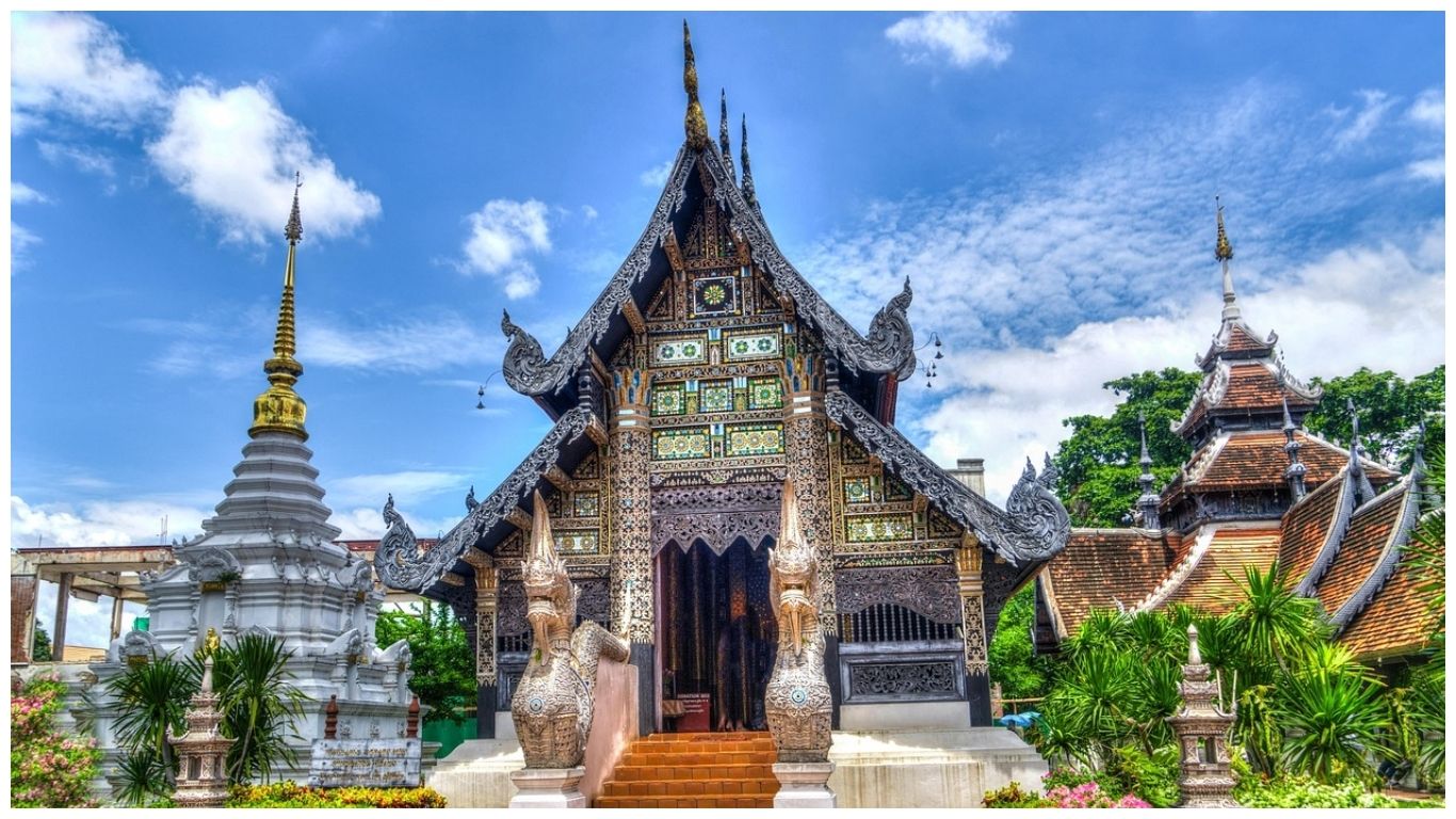 An ornate Buddhist temple in Chiang Mai, one of the best places to visit in Thailand, featuring intricate gold carvings and traditional Lanna architecture under a bright blue sky