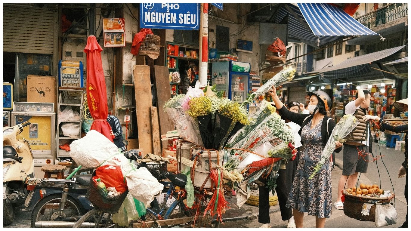 A street vendor on Nguyen Sieu street in Hanoi Old Quarter with a bicycle loaded with colorful flowers, a typical scene before starting day trips from Hanoi Vietnam