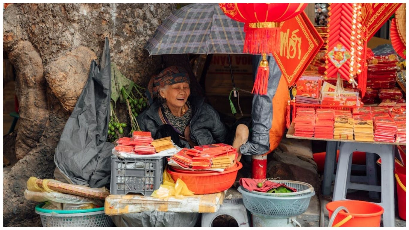 A local Vietnamese woman selling red envelopes and Tet decorations at a street market, showcasing the authentic culture found on a Central Vietnam itinerary