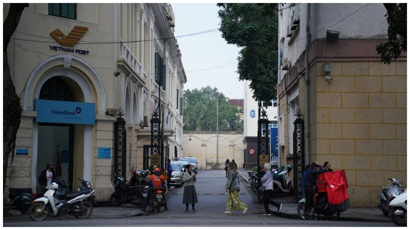 Tourists and locals walking near the historic Vietnam Post building and French colonial architecture in the Hanoi French Quarter