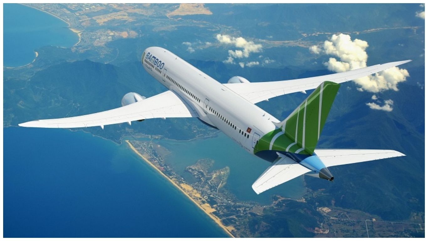 An aerial view of a Bamboo Airways plane flying over the scenic coastline of Vietnam, representing the fastest way on how to get to Phu Quoc from Ho Chi Minh