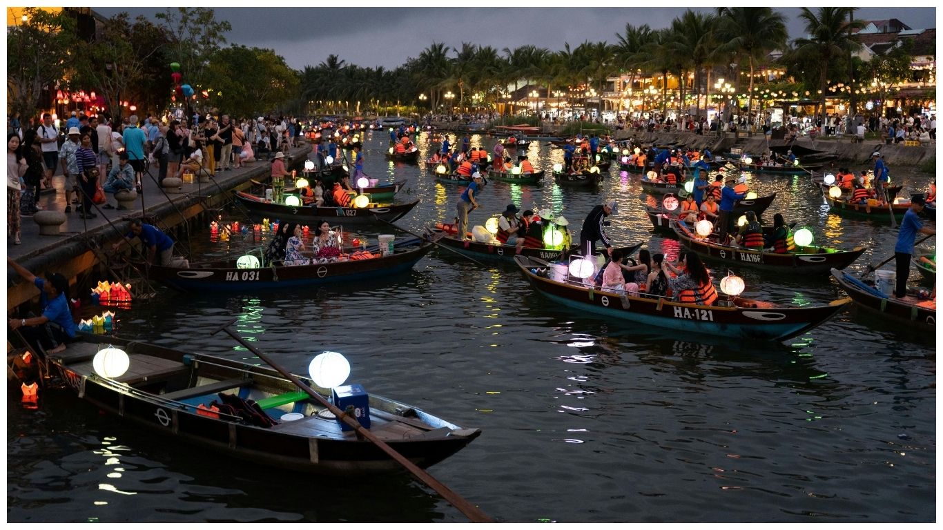 Hundreds of small wooden boats with glowing lanterns floating on the Hoai River during the Hoi An Lantern Festival at night in Vietnam