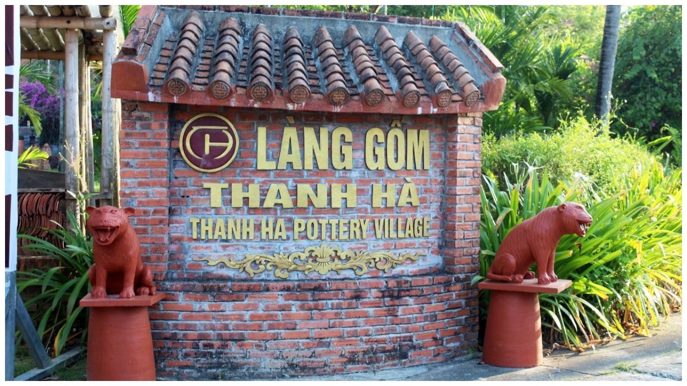 The brick entrance sign of Thanh Ha Pottery Village Hoi An featuring gold lettering and traditional terracotta tiger statues on either side