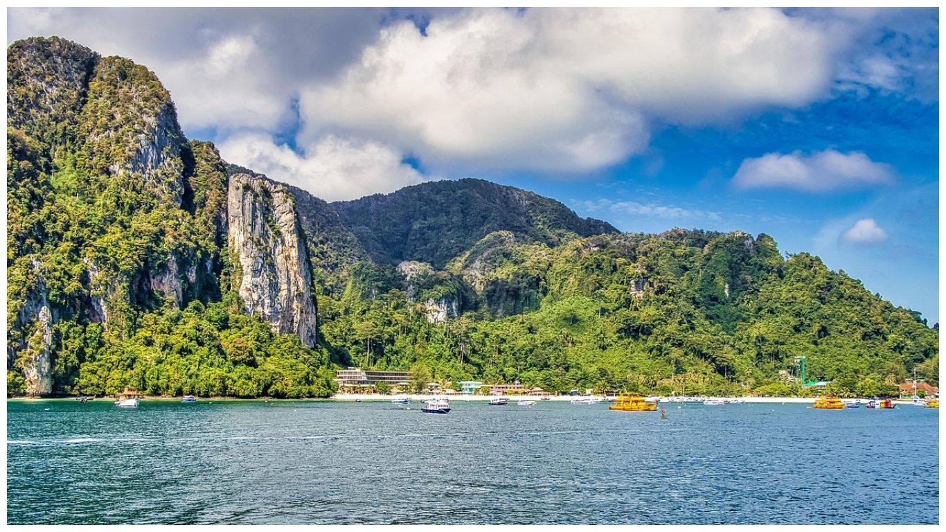 Dramatic limestone cliffs and lush green hills overlooking a bay with scattered boats in Krabi, one of the best places to visit in Thailand for a quiet escape