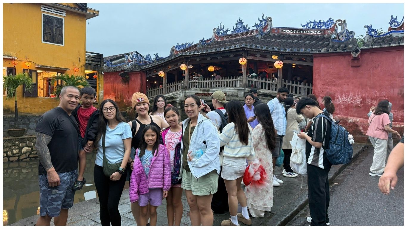 A happy family posing in front of the Japanese Covered Bridge during a guided tour with Indochina Voyages, discovering the best things to do in Hoi An