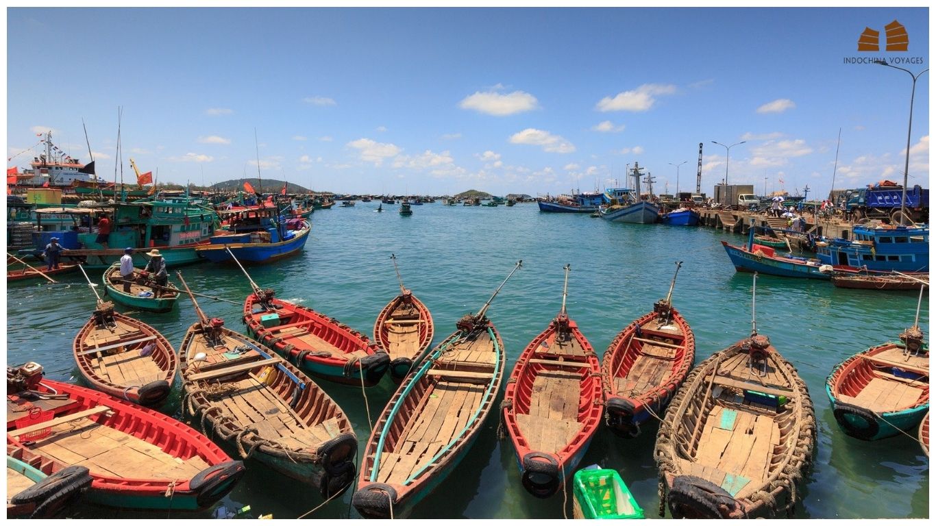 Colorful traditional wooden fishing boats docked at a busy harbor in Phu Quoc, Vietnam under a clear blue sky