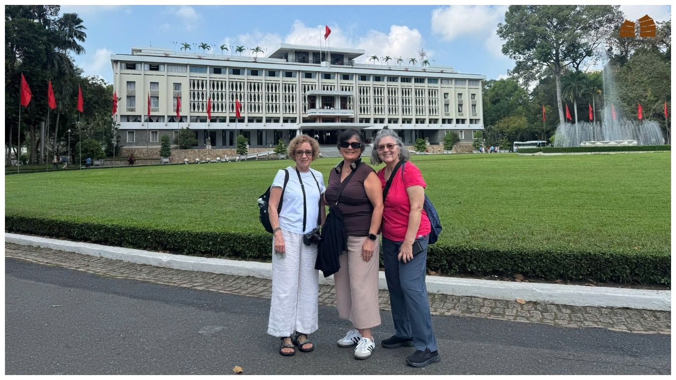 A group of happy tourists posing in front of the Independence Palace in Ho Chi Minh City after completing their day trips from Saigon