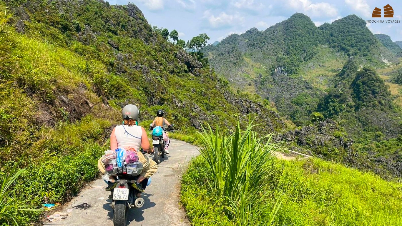Riders on motorbikes along a narrow mountain road in Ha Giang Loop