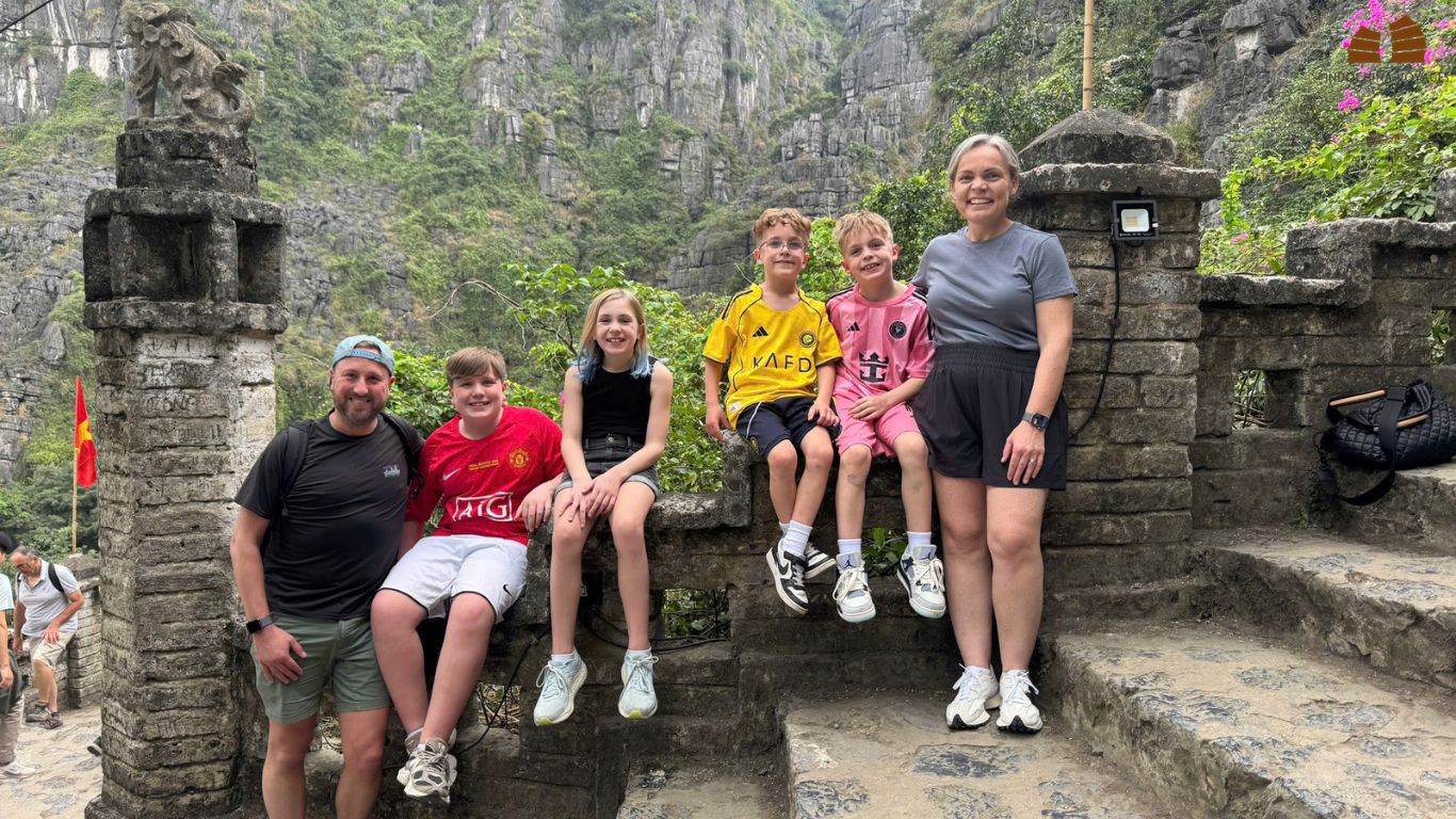 Family posing at a stone viewpoint among limestone mountains in Vietnam.